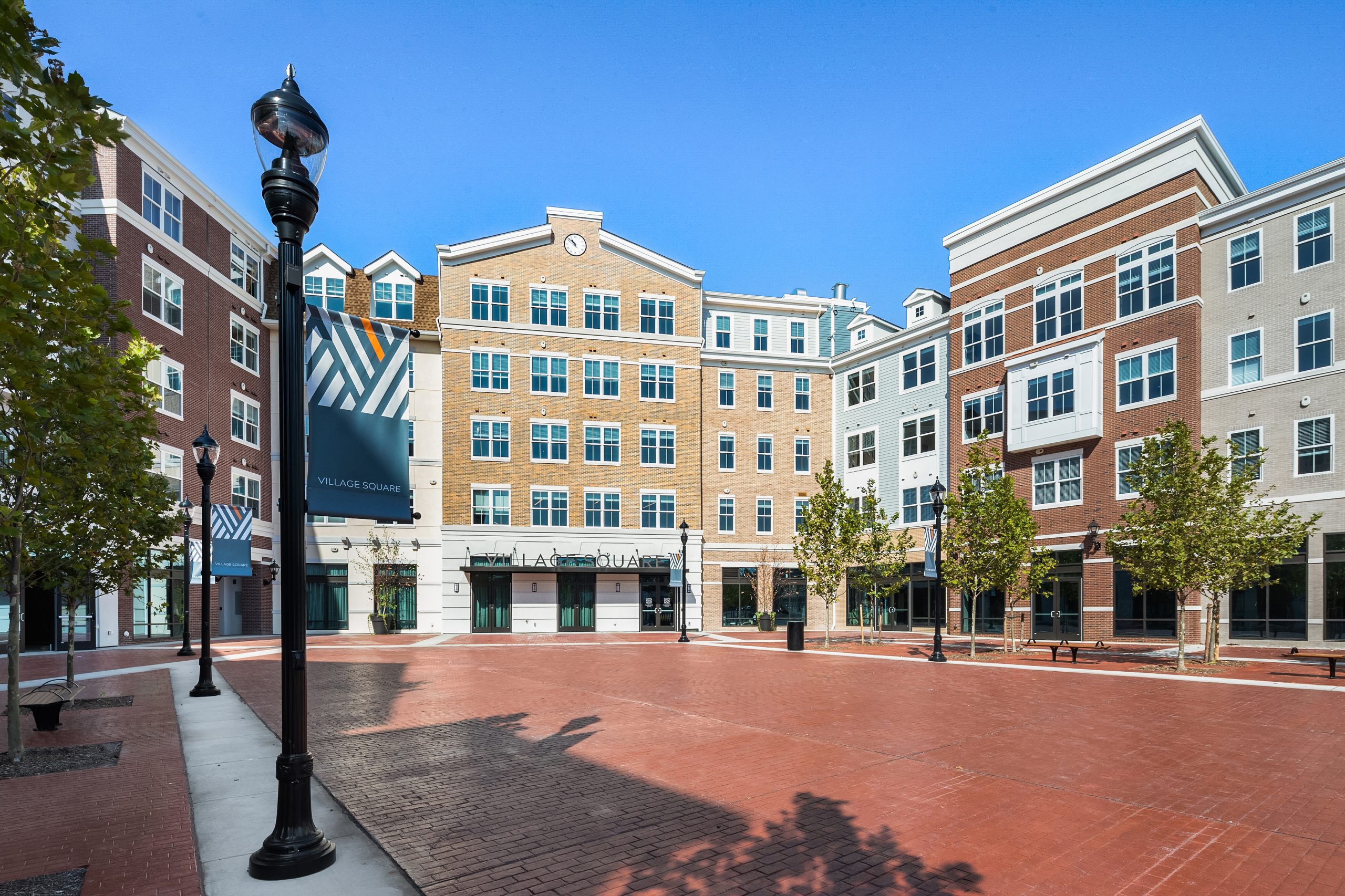 Multi-story buildings with a red-paved square in front of them.